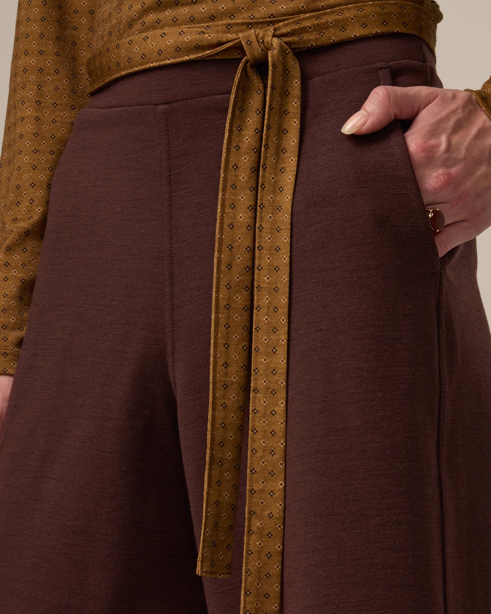 Model wearing Lane Wide Leg Ponte Pant in Espresso, a warm brown color. Lane Wide Leg Ponte Pant is a merino wool pant with pockets available in sizes XS-3X Regular, XS-XXL Long.