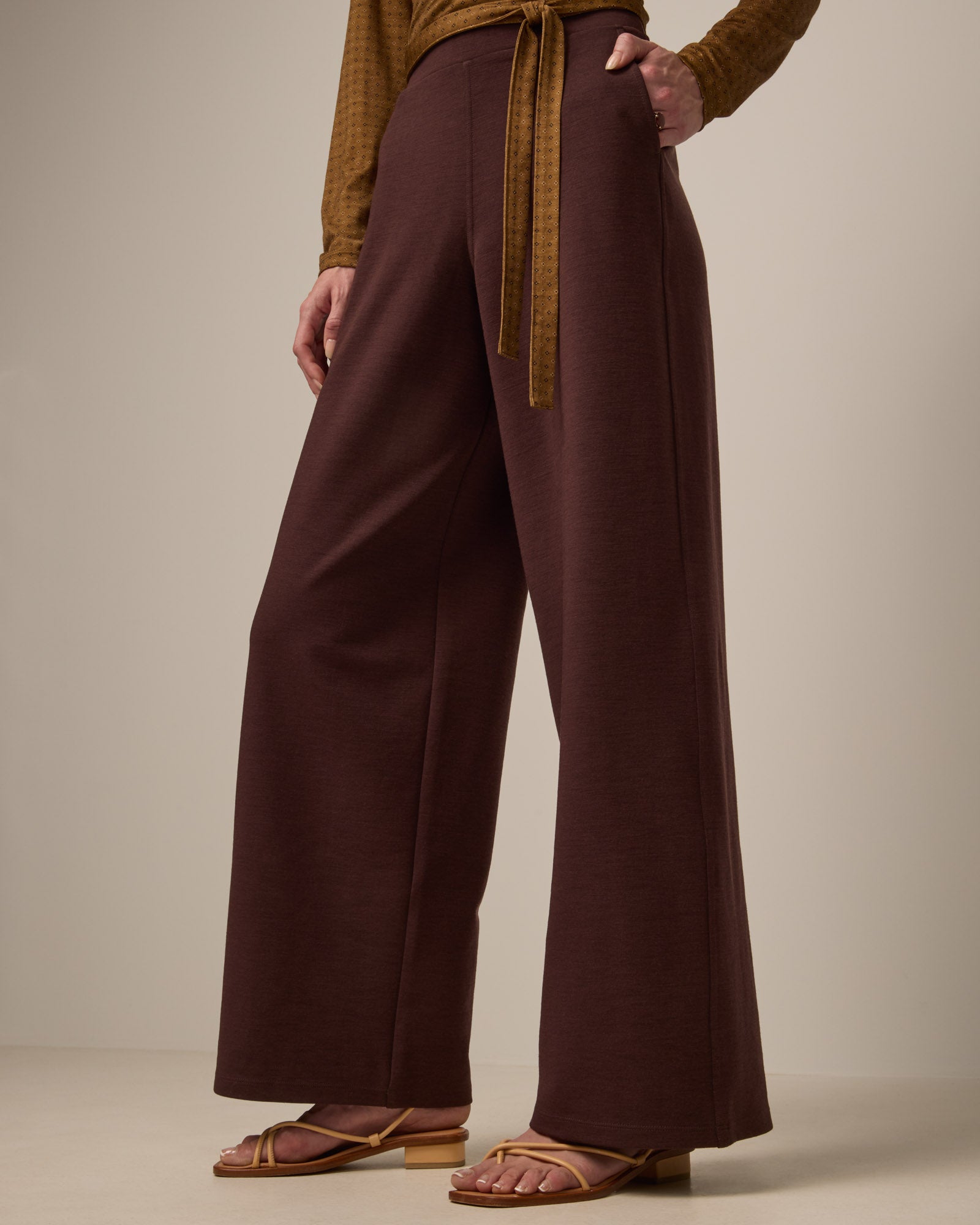 Model wearing Lane Wide Leg Ponte Pant in Espresso, a warm brown color. Lane Wide Leg Ponte Pant is a merino wool pant with pockets available in sizes XS-3X Regular, XS-XXL Long.