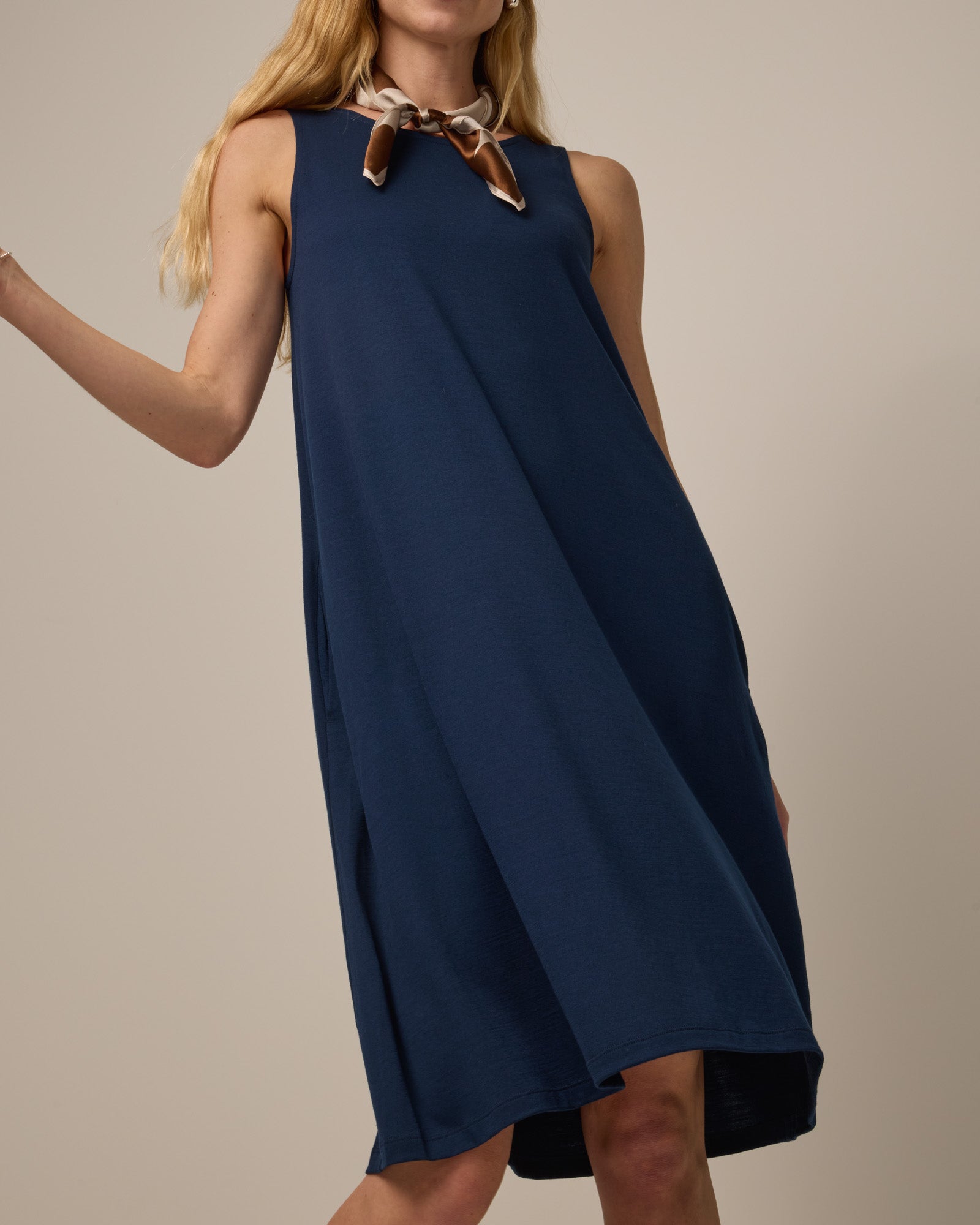 Model wearing Camellia Tank Dress in Marine Blue, a deep royal blue color. Camellia Tank Dress is a merino wool sleeveless, crew neck, knee length swing dress with pockets available in sizes XS-3X Regular, XS-3X Long.