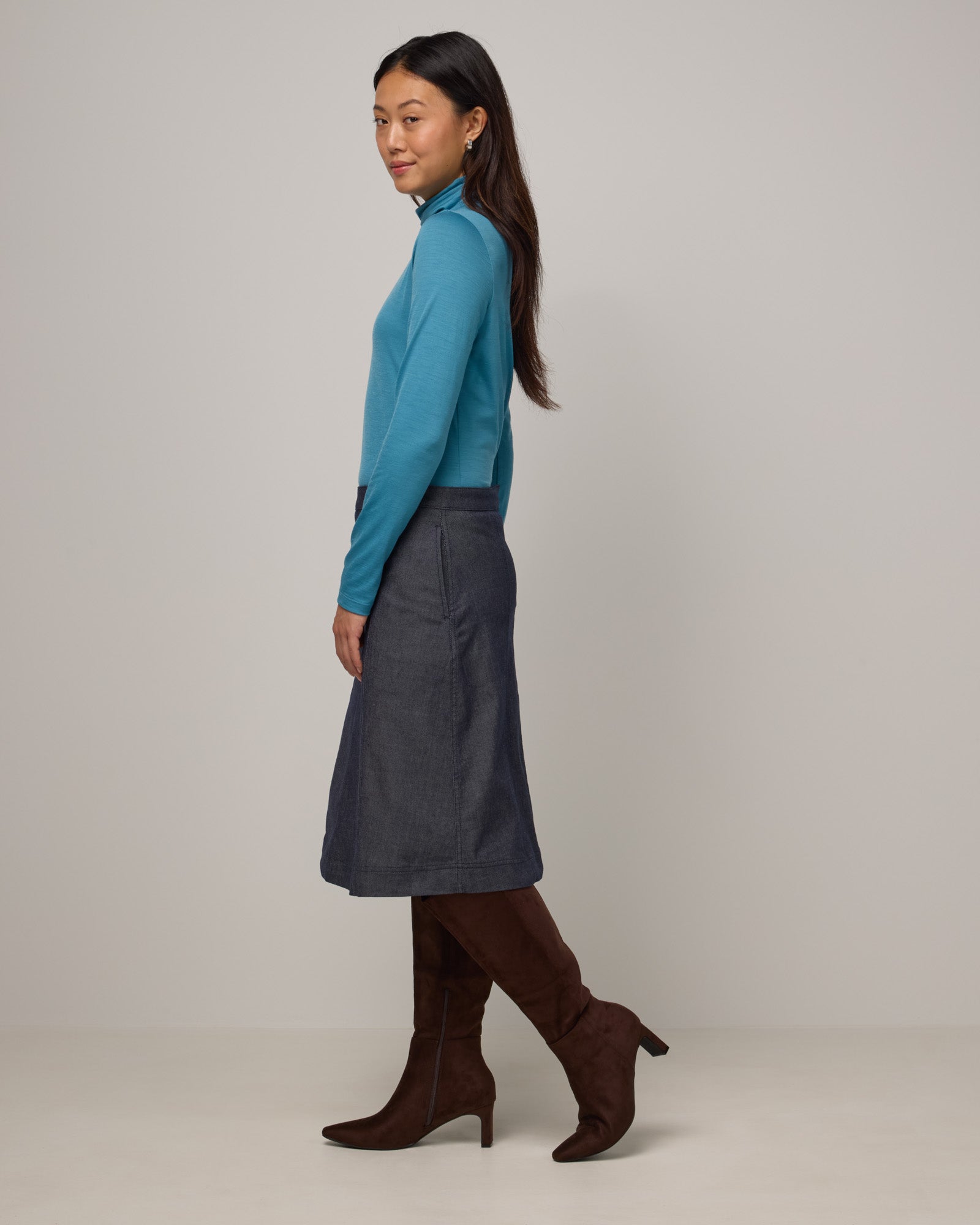Model wearing Addison Turtleneck Top in Alpine Blue, a glacier ice blue color. Addison Turtleneck Top is a merino wool long sleeve, turtleneck, slim fit top available in sizes XS-3X.