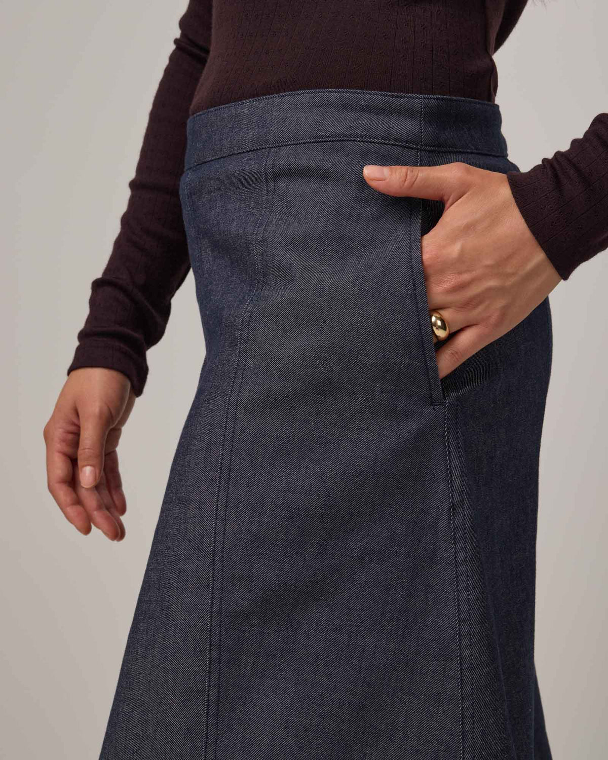 Model wearing Joy Denim Panel Skirt in Indigo Blue. Joy Denim Panel Skirt is a merino wool knee-length skirt available in sizes XS-XXL.