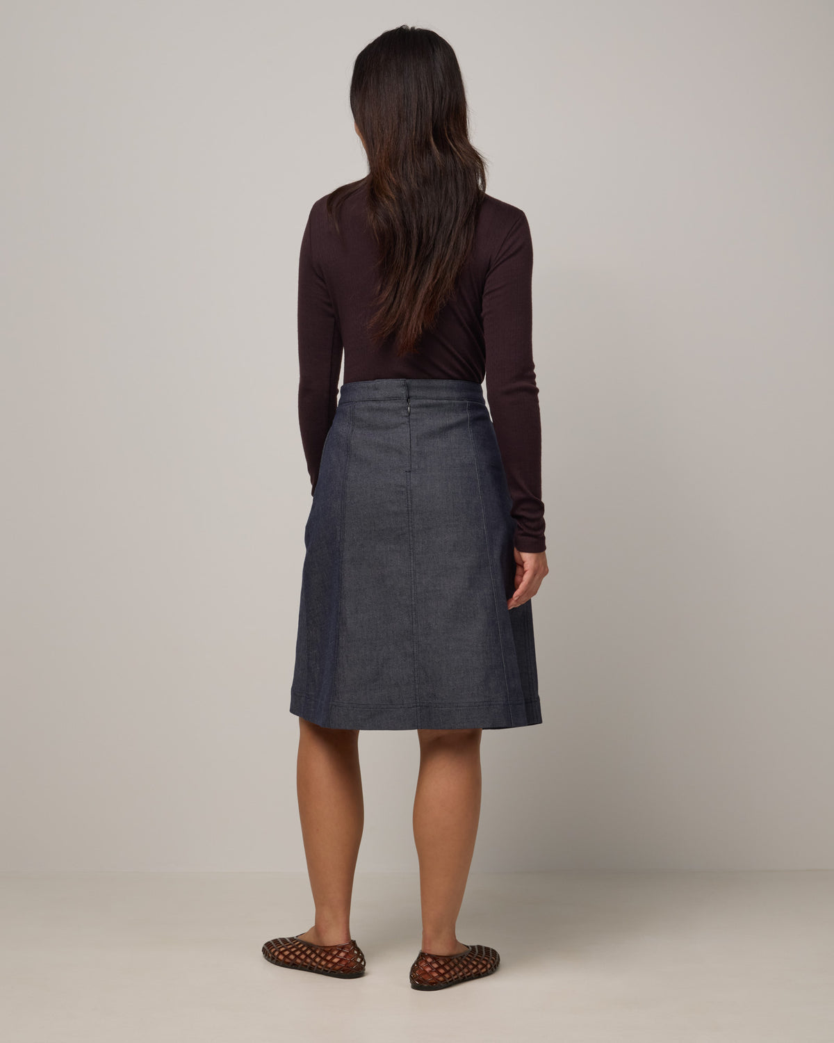 Model wearing Joy Denim Panel Skirt in Indigo Blue. Joy Denim Panel Skirt is a merino wool knee-length skirt available in sizes XS-XXL.