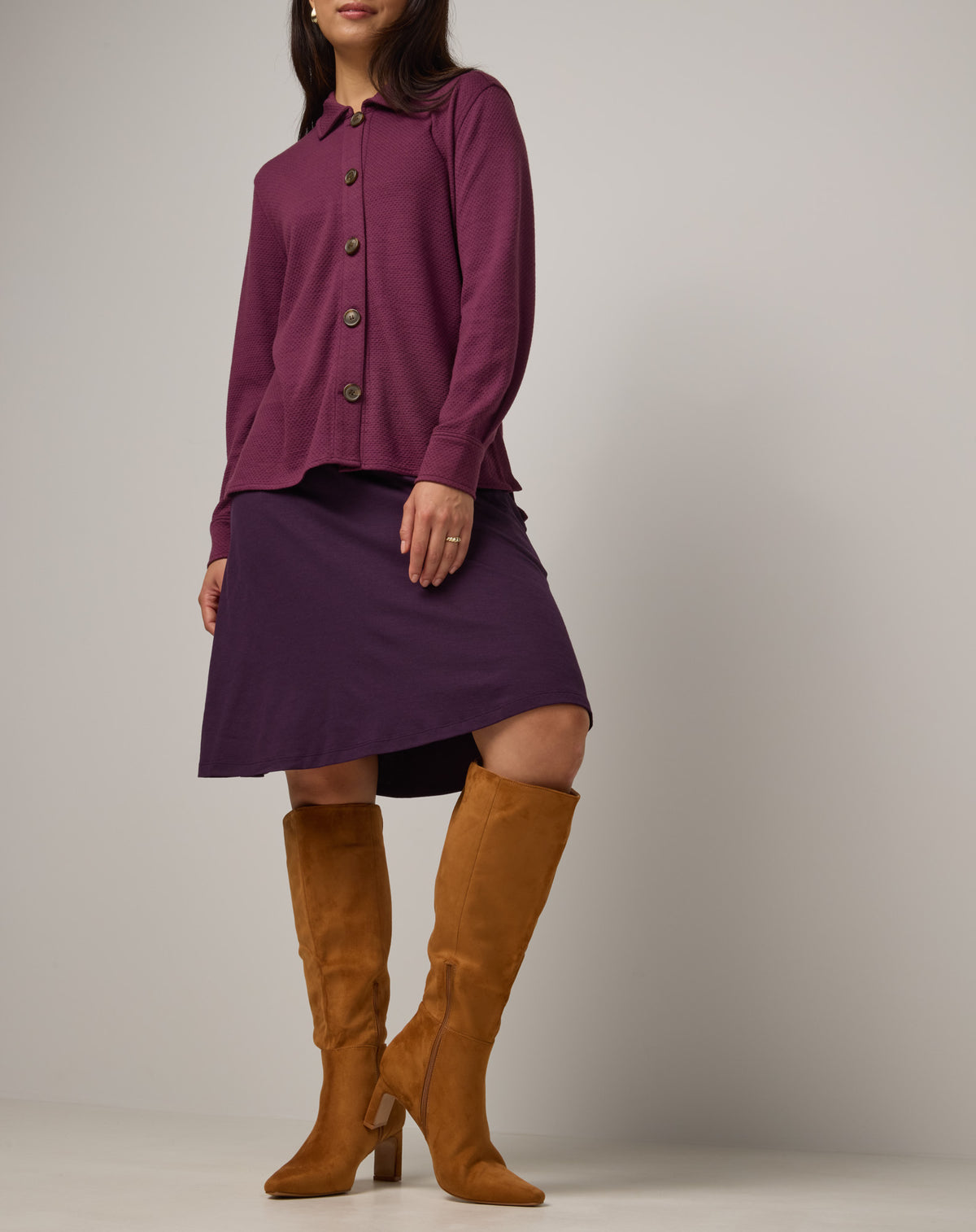 Model wearing Helena Skirt in Cassis, a deep purple color. Helena Skirt is a merino wool knee length skirt with pockets available in sizes XS-3X.