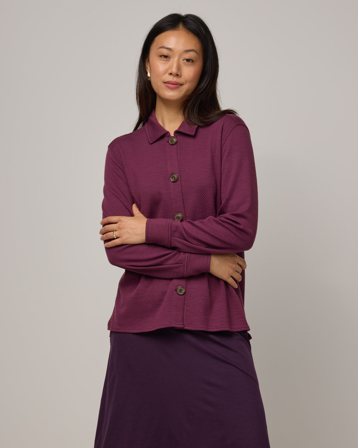 Model wearing Dani Relaxed Button-Front Shirt in Plum, a reddish purple color. Dani Relaxed Button-Front Shirt is a merino wool long sleeve, collared button-down shirt available in sizes XS-3X.