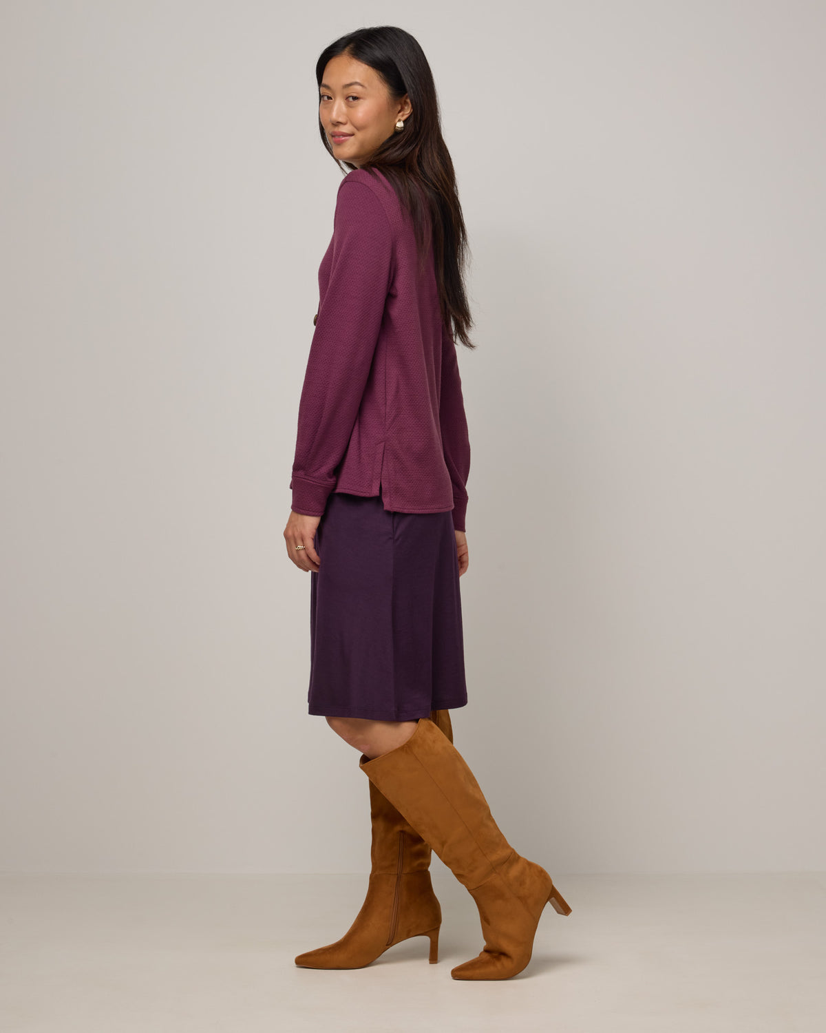 Model wearing Helena Skirt in Cassis, a deep purple color. Helena Skirt is a merino wool knee length skirt with pockets available in sizes XS-3X.
