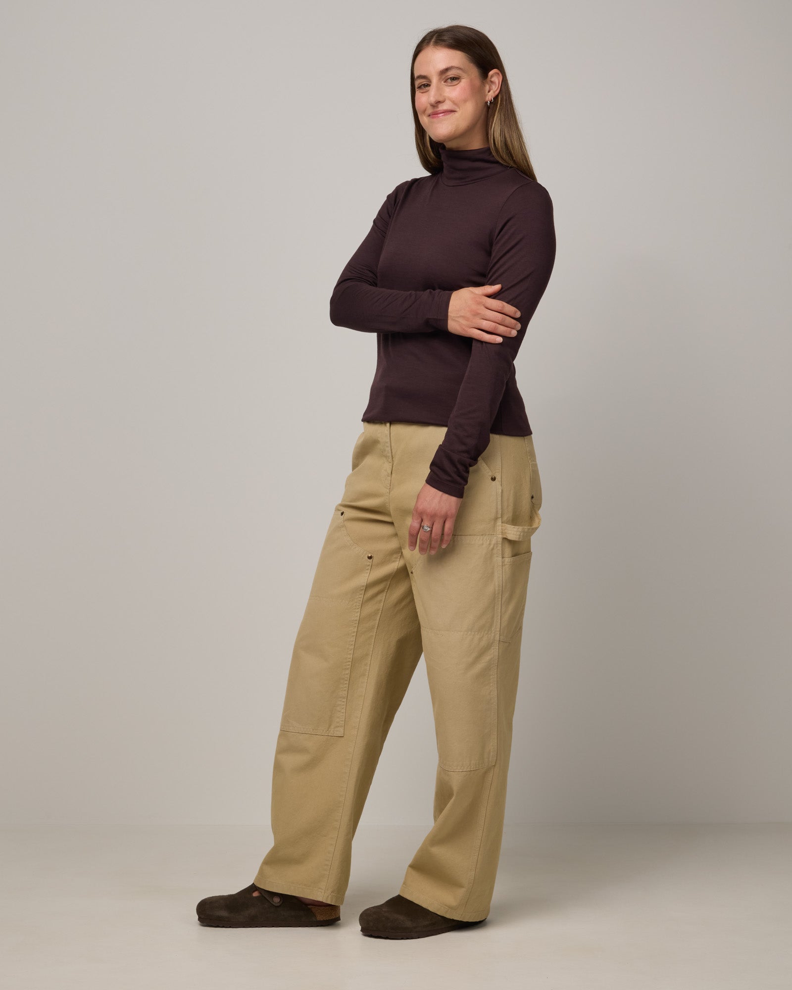 Model wearing Addison Turtleneck Top in Espresso, a dark brown color. Addison Turtleneck Top is a merino wool long sleeve, turtleneck, slim fit top available in sizes XS-3X.