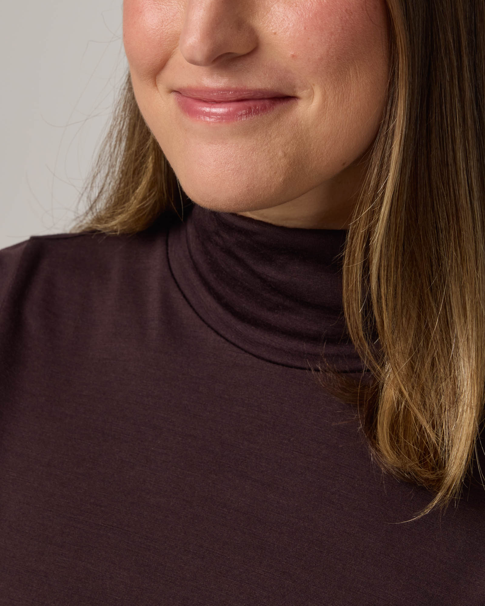 Model wearing Addison Turtleneck Top in Espresso, a dark brown color. Addison Turtleneck Top is a merino wool long sleeve, turtleneck, slim fit top available in sizes XS-3X.