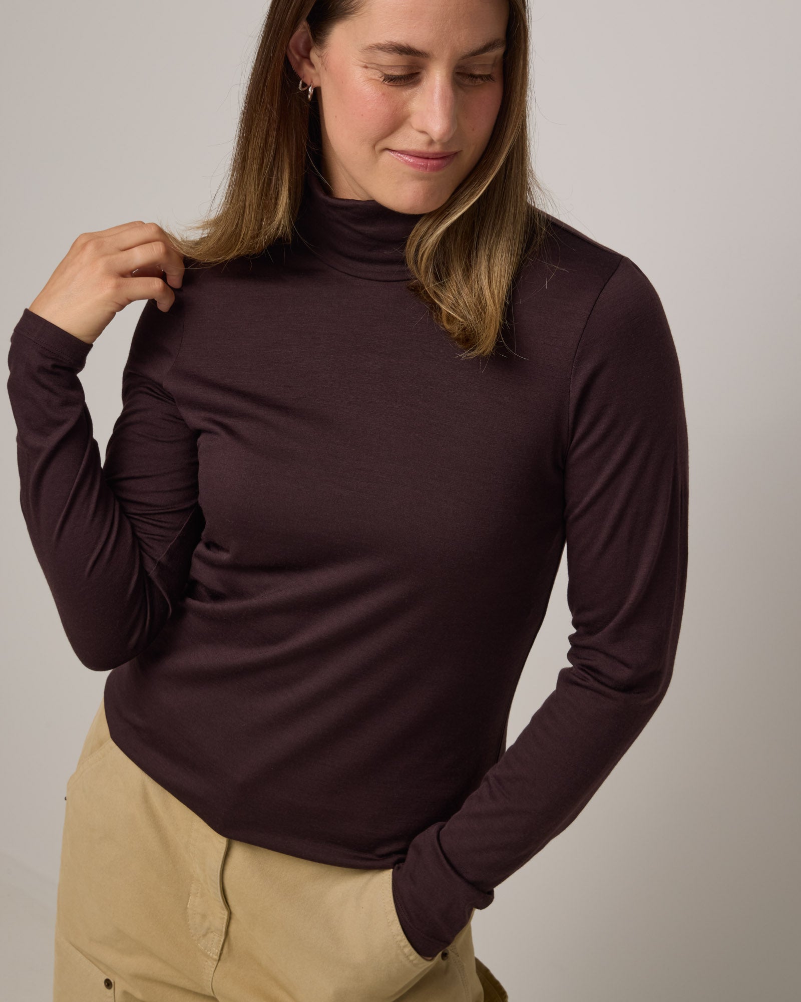 Model wearing Addison Turtleneck Top in Espresso, a dark brown color. Addison Turtleneck Top is a merino wool long sleeve, turtleneck, slim fit top available in sizes XS-3X.