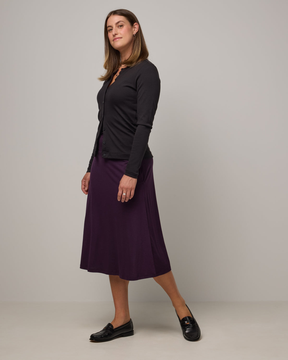 Model wearing Helena Midi Skirt in Cassis, a deep purple color. Helena Midi Skirt is a merino wool midi skirt with pockets available in sizes XS-3X.