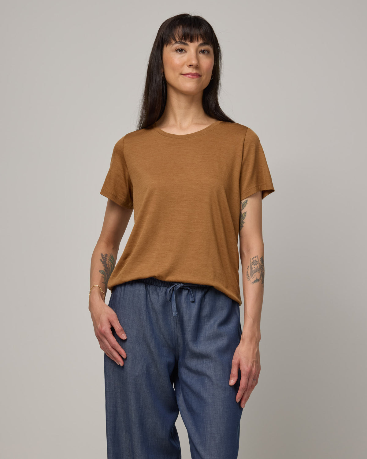 Model wearing Zoe Easy Crew Neck Tee in Camel, a caramel brown color. Zoe Easy Crew Neck Tee is a merino wool short sleeve, crew neck, regular fit tee available in sizes XS-3X.