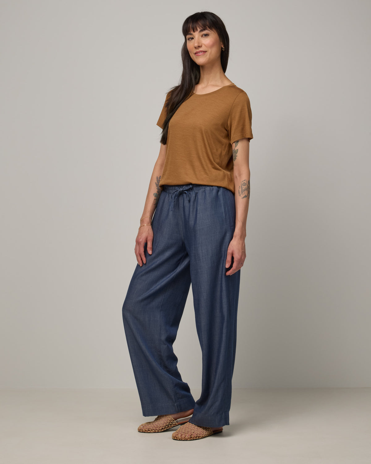 Model wearing Zoe Easy Crew Neck Tee in Camel, a caramel brown color. Zoe Easy Crew Neck Tee is a merino wool short sleeve, crew neck, regular fit tee available in sizes XS-3X.