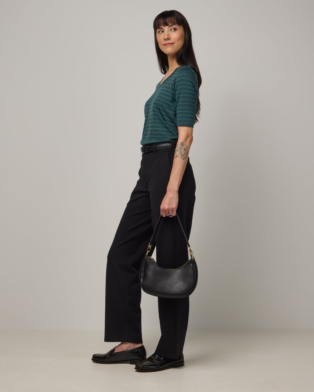 Model wearing Celine Signature Elbow-Sleeve Tee in Pine & Emerald Stripe, a dark green stripe. Celine Signature Elbow Sleeve Tee is a merino wool scoop neck half-sleeve tee available in sizes XS-3X.