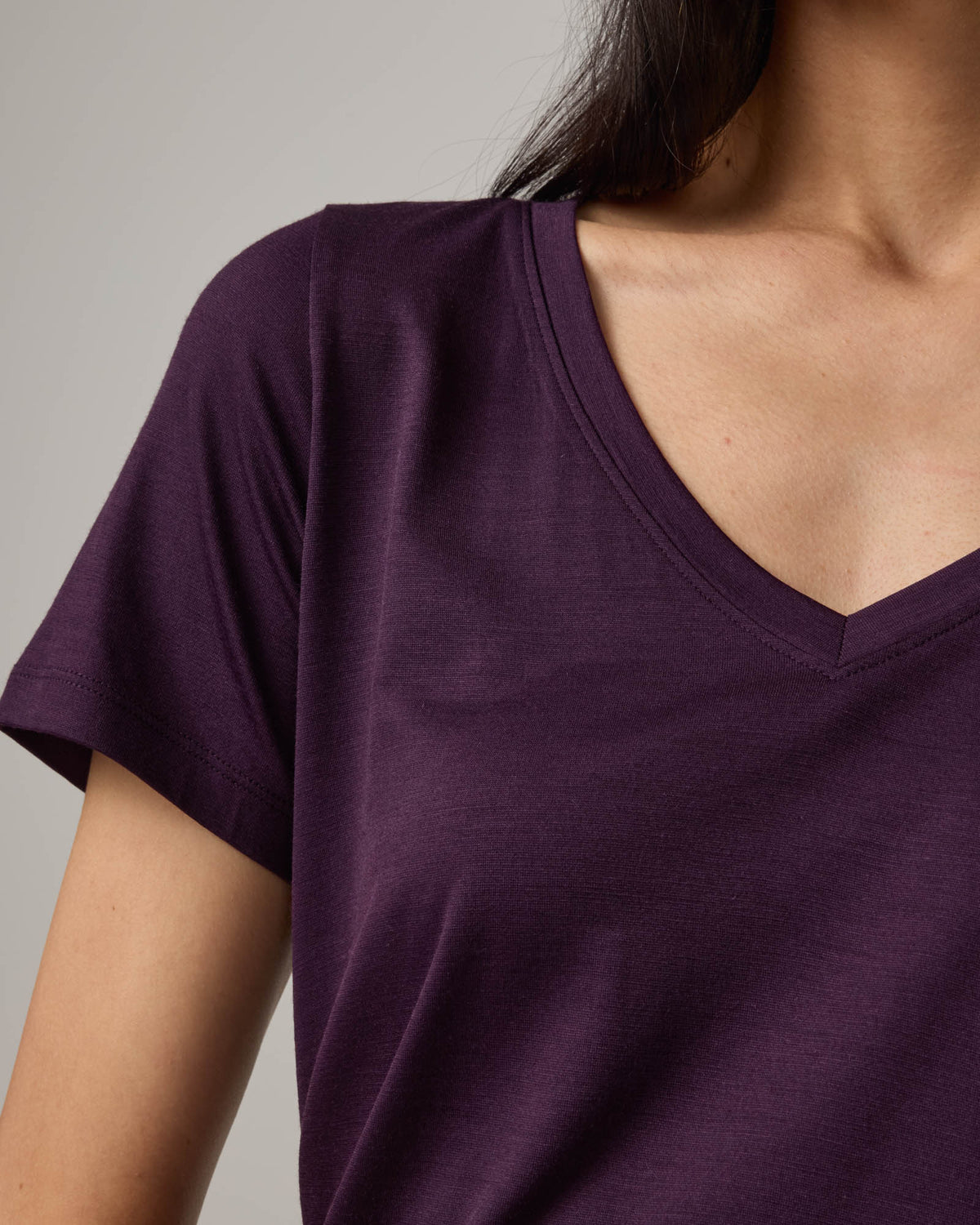 Model wearing Morgan V-Neck Tee in Cassis, a deep purple color. Morgan V-Neck Tee is a merino wool short sleeve, v-neck, regular fit tee available in sizes XS-3X.