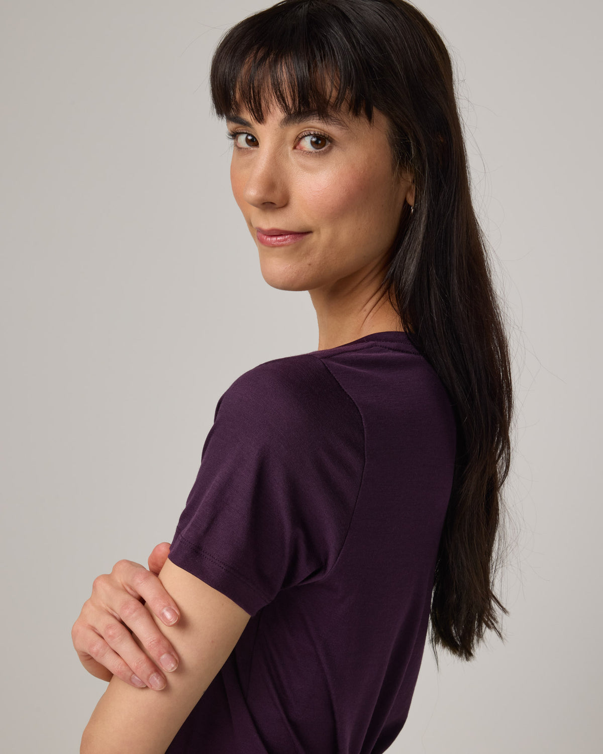 Model wearing Morgan V-Neck Tee in Cassis, a deep purple color. Morgan V-Neck Tee is a merino wool short sleeve, v-neck, regular fit tee available in sizes XS-3X.
