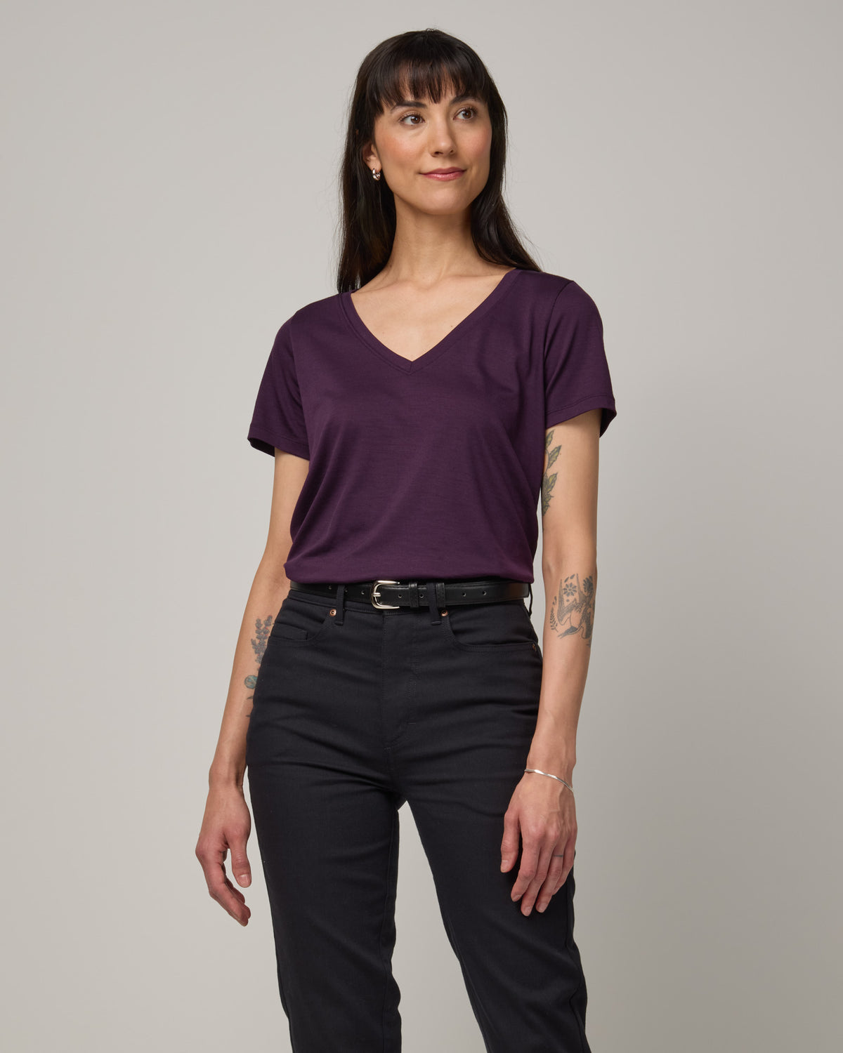 Model wearing Morgan V-Neck Tee in Cassis, a deep purple color. Morgan V-Neck Tee is a merino wool short sleeve, v-neck, regular fit tee available in sizes XS-3X.