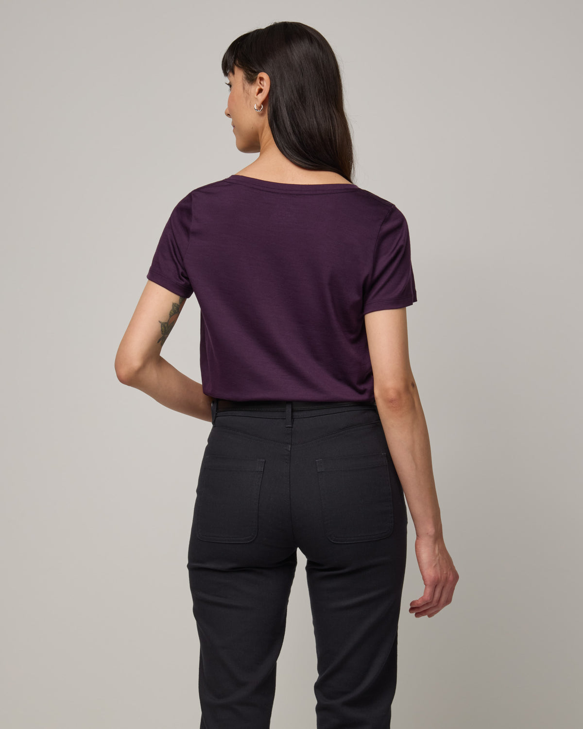 Model wearing Morgan V-Neck Tee in Cassis, a deep purple color. Morgan V-Neck Tee is a merino wool short sleeve, v-neck, regular fit tee available in sizes XS-3X.