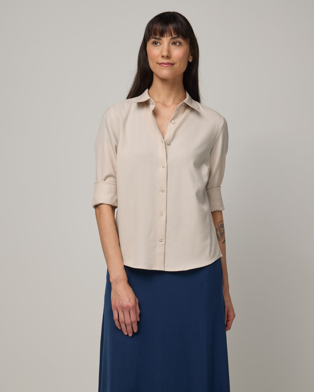 Model wearing Tiffany Button-Front Shirt in Oatmeal, a soft cream color. Tiffany Button-Front Shirt is a merino wool long sleeve collared shirt available in sizes XS-XXL.