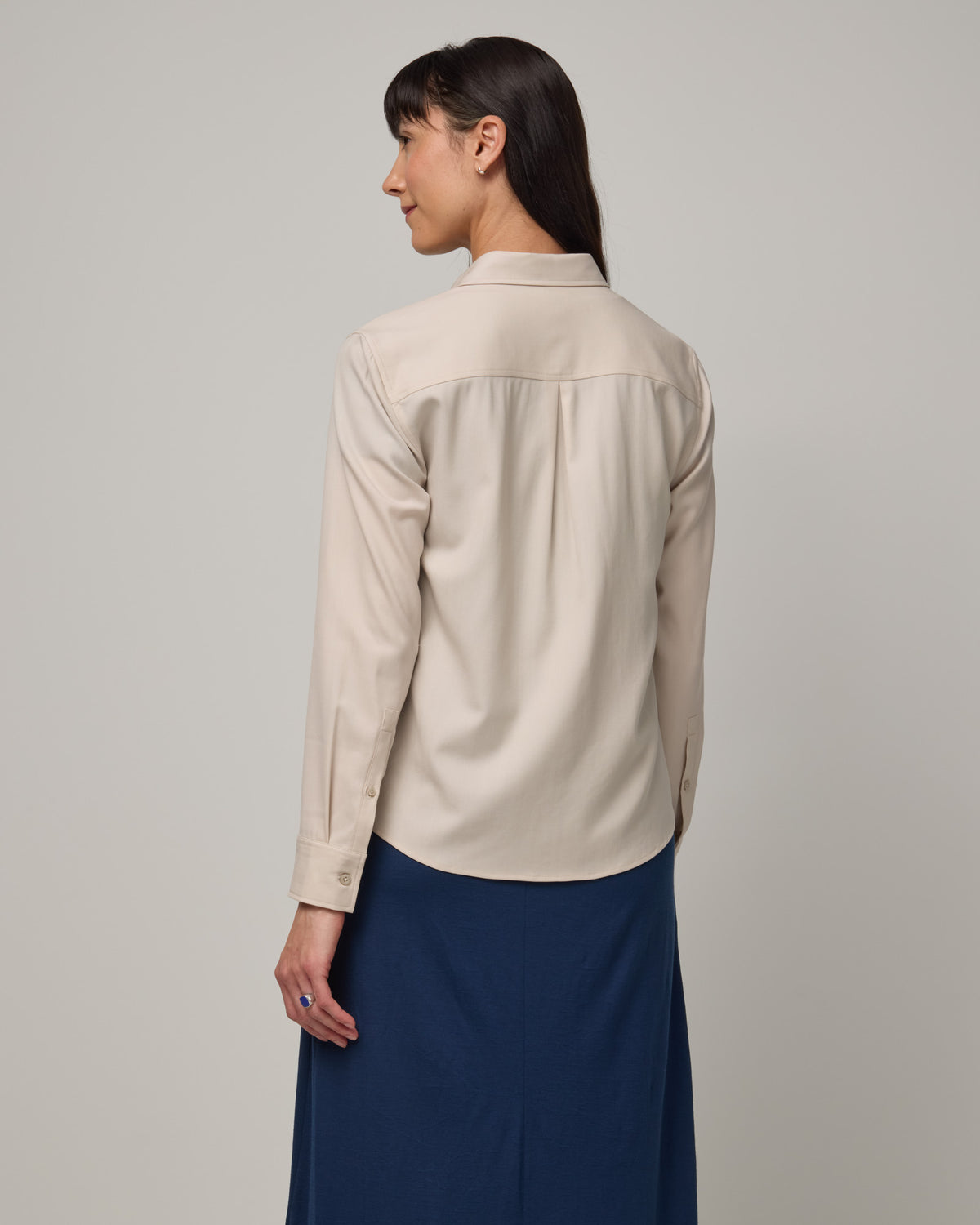 Model wearing Tiffany Button-Front Shirt in Oatmeal, a soft cream color. Tiffany Button-Front Shirt is a merino wool long sleeve collared shirt available in sizes XS-XXL.