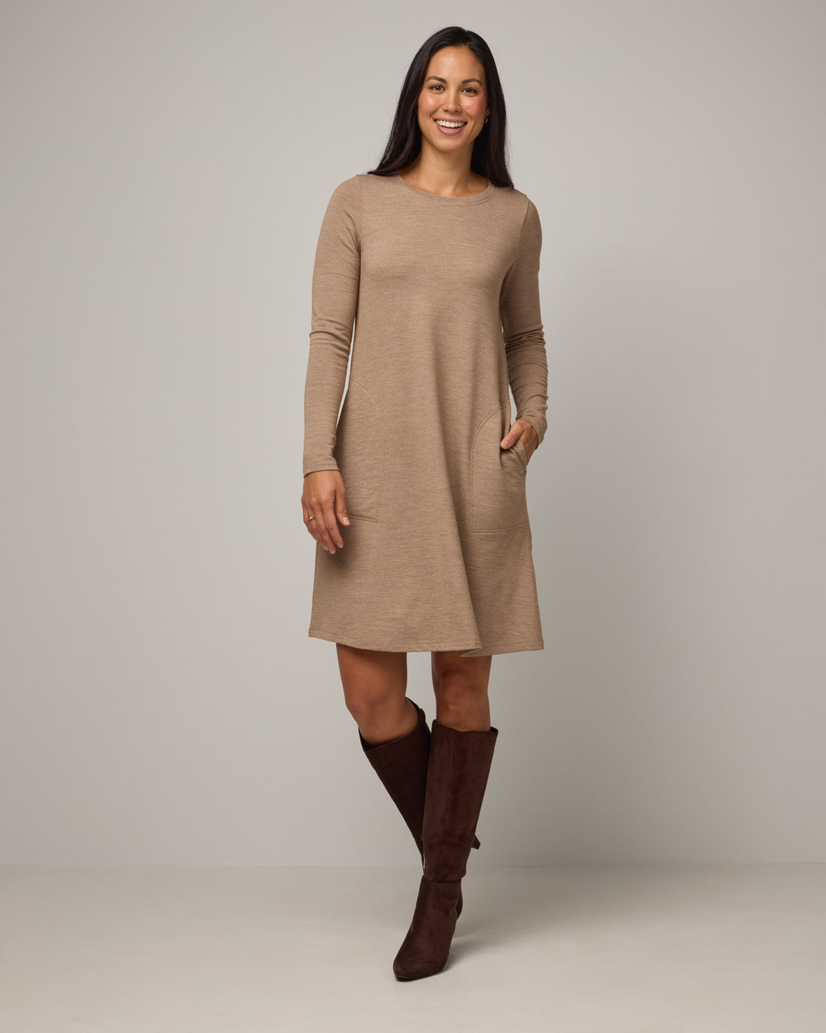 Model wearing Eliza Swing Dress in Camel Heather, a warm heathered tan. Eliza Swing Dress is a merino wool long sleeve, crew neck, knee length swing dress with pockets available in sizes XS-3X Regular, XS-3X Long.