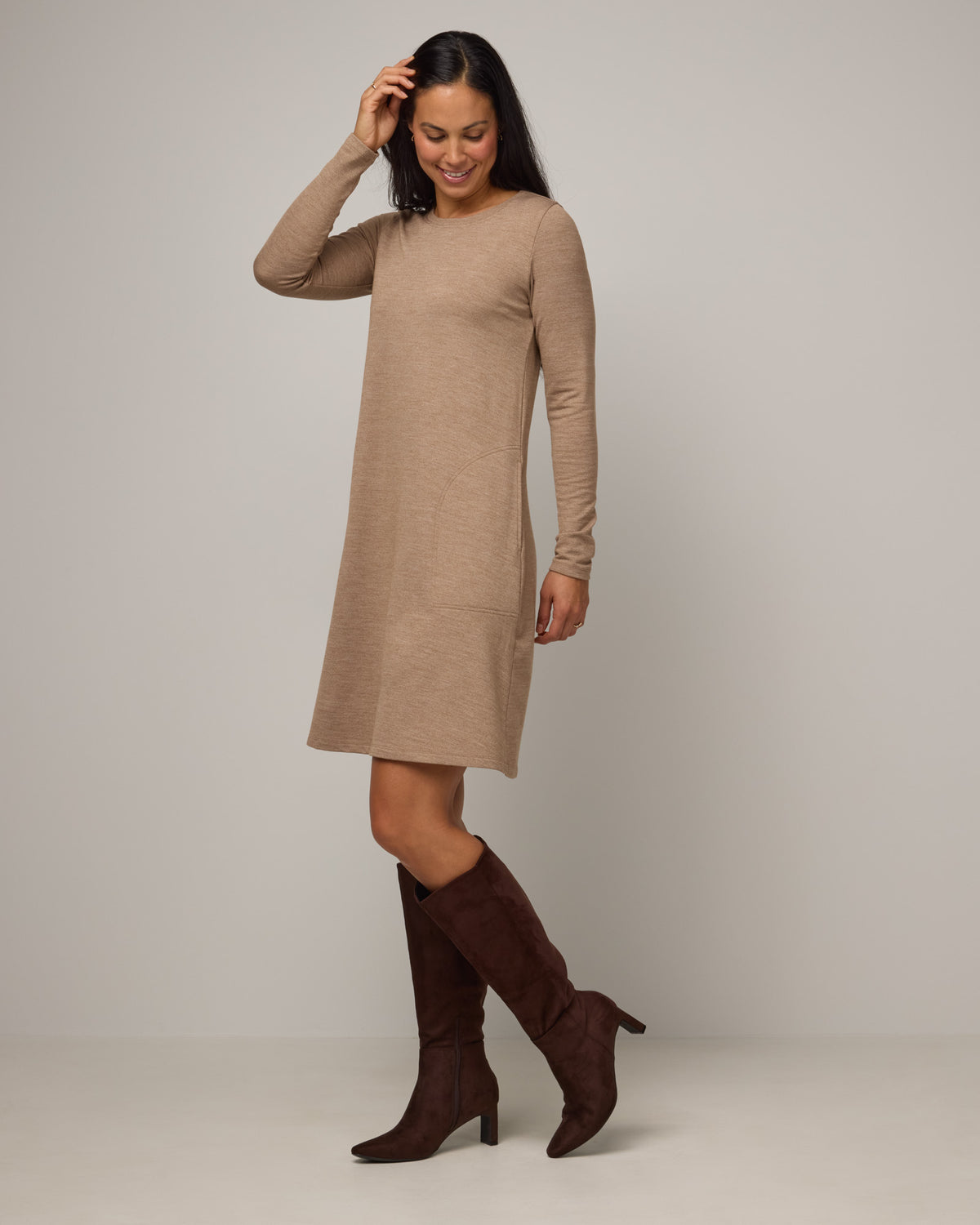 Model wearing Eliza Swing Dress in Camel Heather, a warm heathered tan. Eliza Swing Dress is a merino wool long sleeve, crew neck, knee length swing dress with pockets available in sizes XS-3X Regular, XS-3X Long.