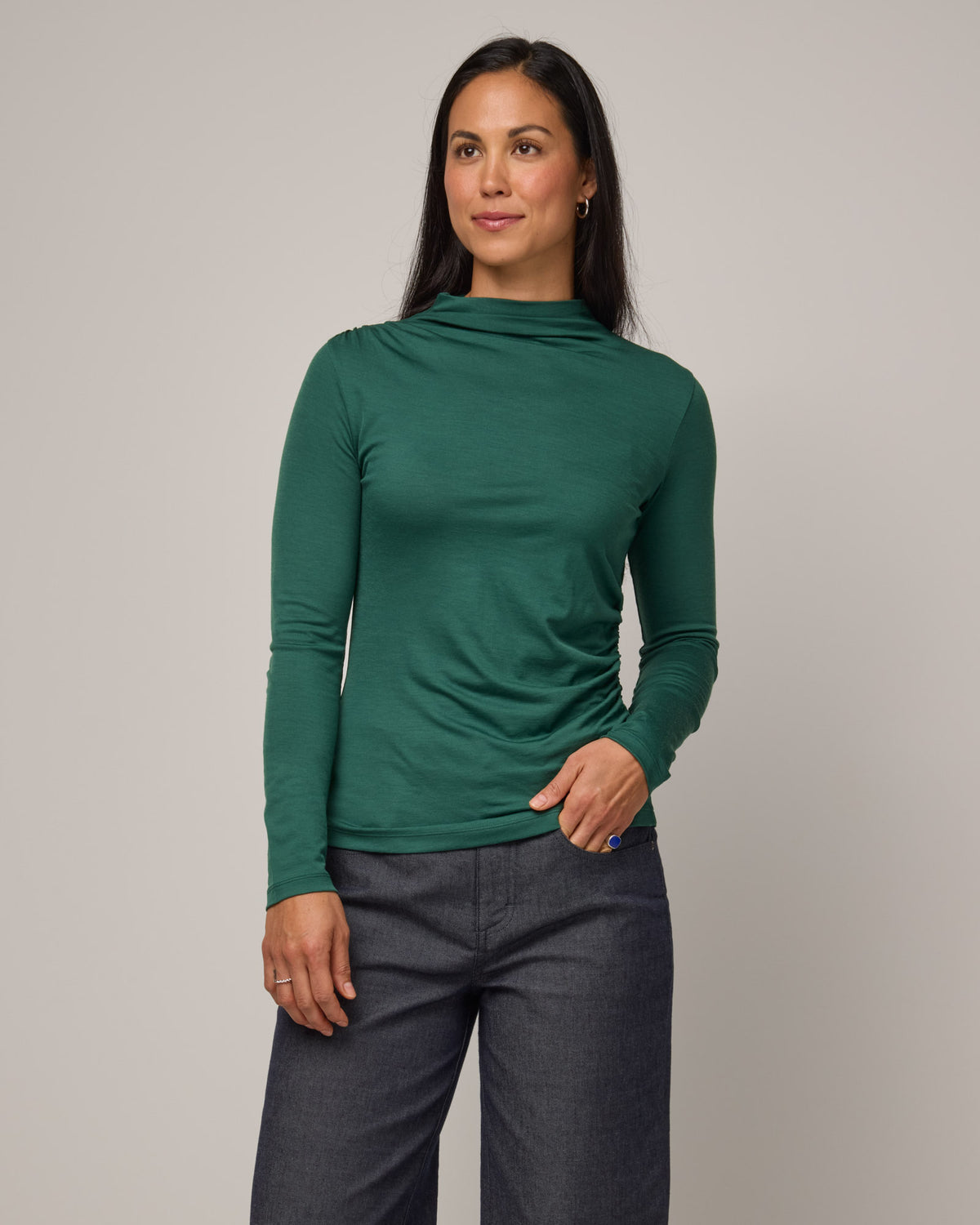 Model wearing Katrina Ruched Top in Emerald green. Katrina Ruched Top is a long sleeve, fitted merino wool mock turtleneck top available in sizes XS-XXL.