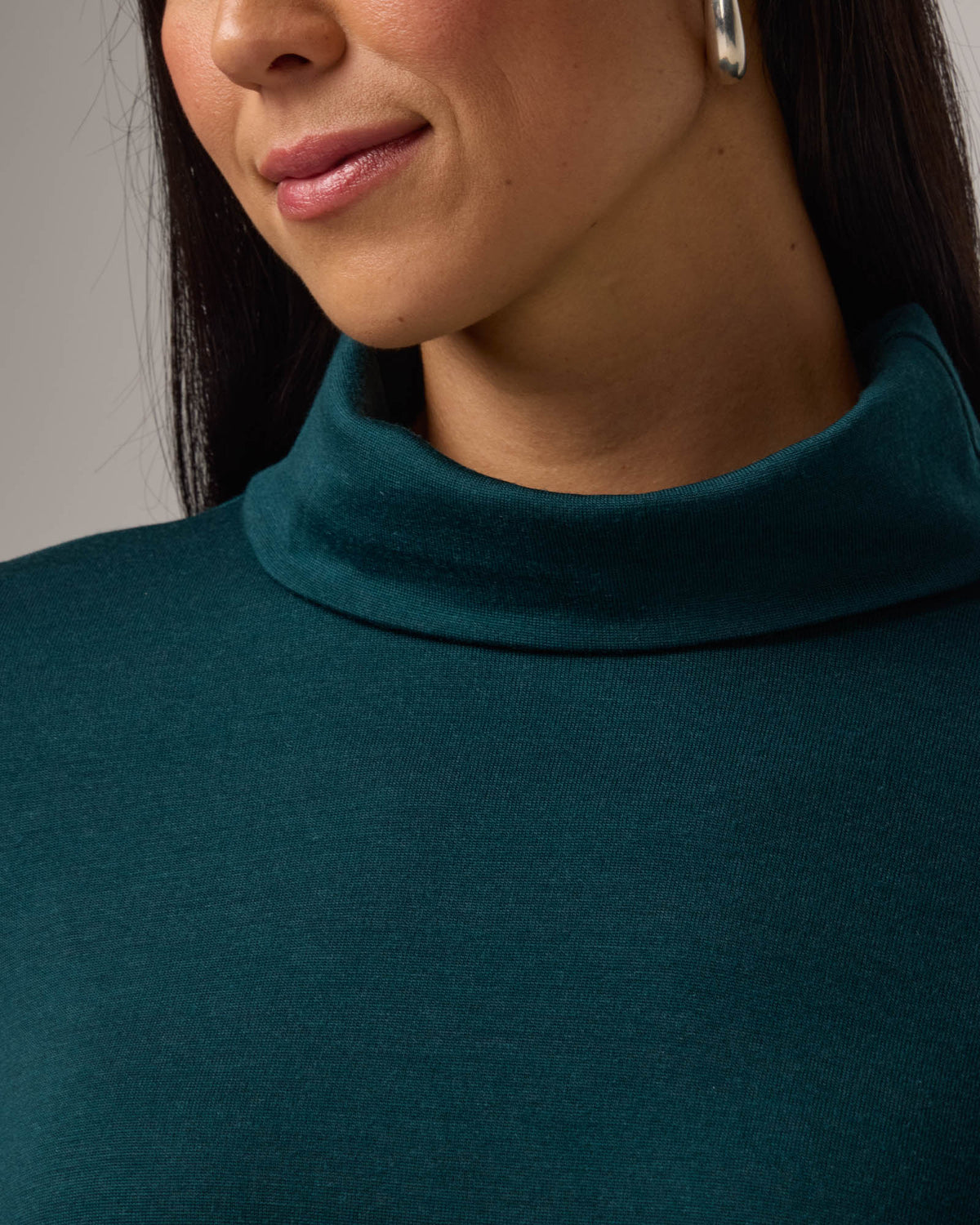 Model wearing Rylie Heavyweight Turtleneck Top in Pine, a dark green color. Rylie Heavyweight Turtleneck Top is a merino wool long sleeve, relaxed fit turtleneck available in sizes XS-3X.
