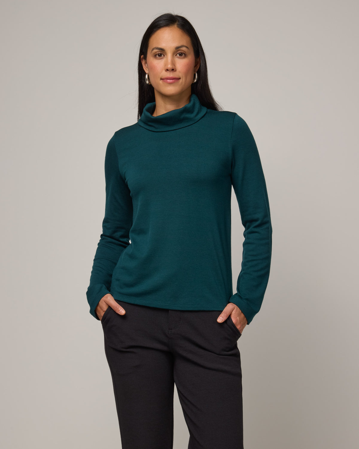 Model wearing Rylie Heavyweight Turtleneck Top in Pine, a dark green color. Rylie Heavyweight Turtleneck Top is a merino wool long sleeve, relaxed fit turtleneck available in sizes XS-3X.