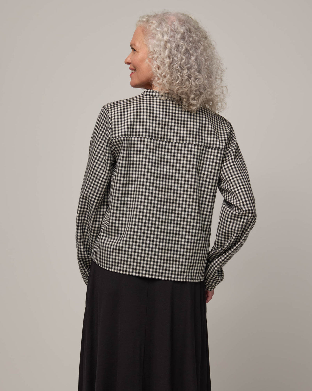 Model wearing Raquel Brushed Twill Top in Black & White Gingham. Raquel Brushed Twill Top is a 100% merino wool long sleeve, split collar button-front shirt available in sizes XS-XXL.