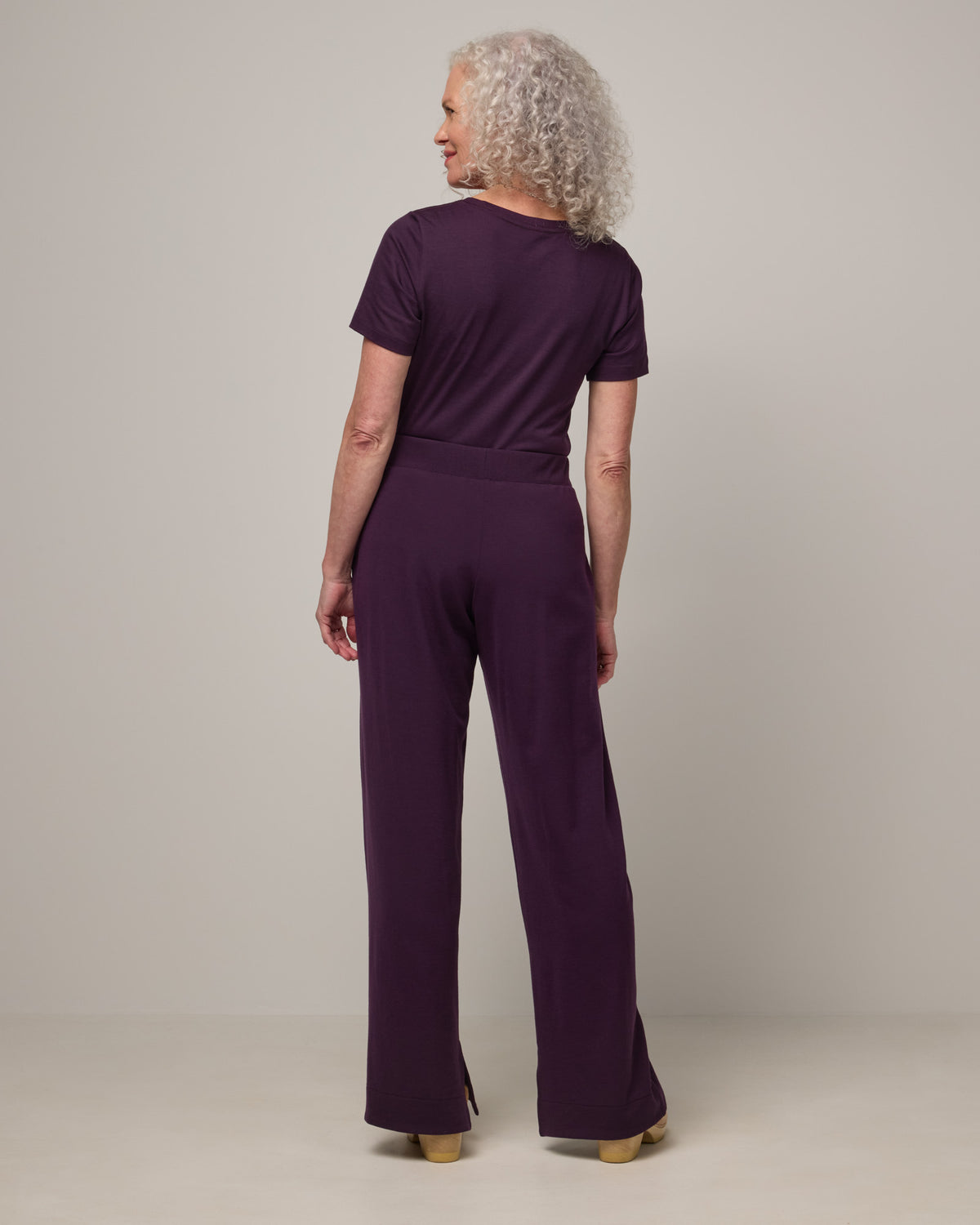 Model wearing Aspen Wide Leg Sweatpantsin Cassis, a deep purple color. Aspen Wide Leg Sweatpant is a merino wool, elastic waist pant available in sizes XS-3X. 