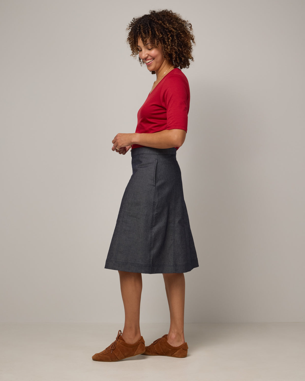 Model wearing Celine Signature Elbow-Sleeve Tee in Cherry Red, a bright red color. Celine Signature Elbow Sleeve Tee is a merino wool scoop neck half-sleeve tee available in sizes XS-3X. 