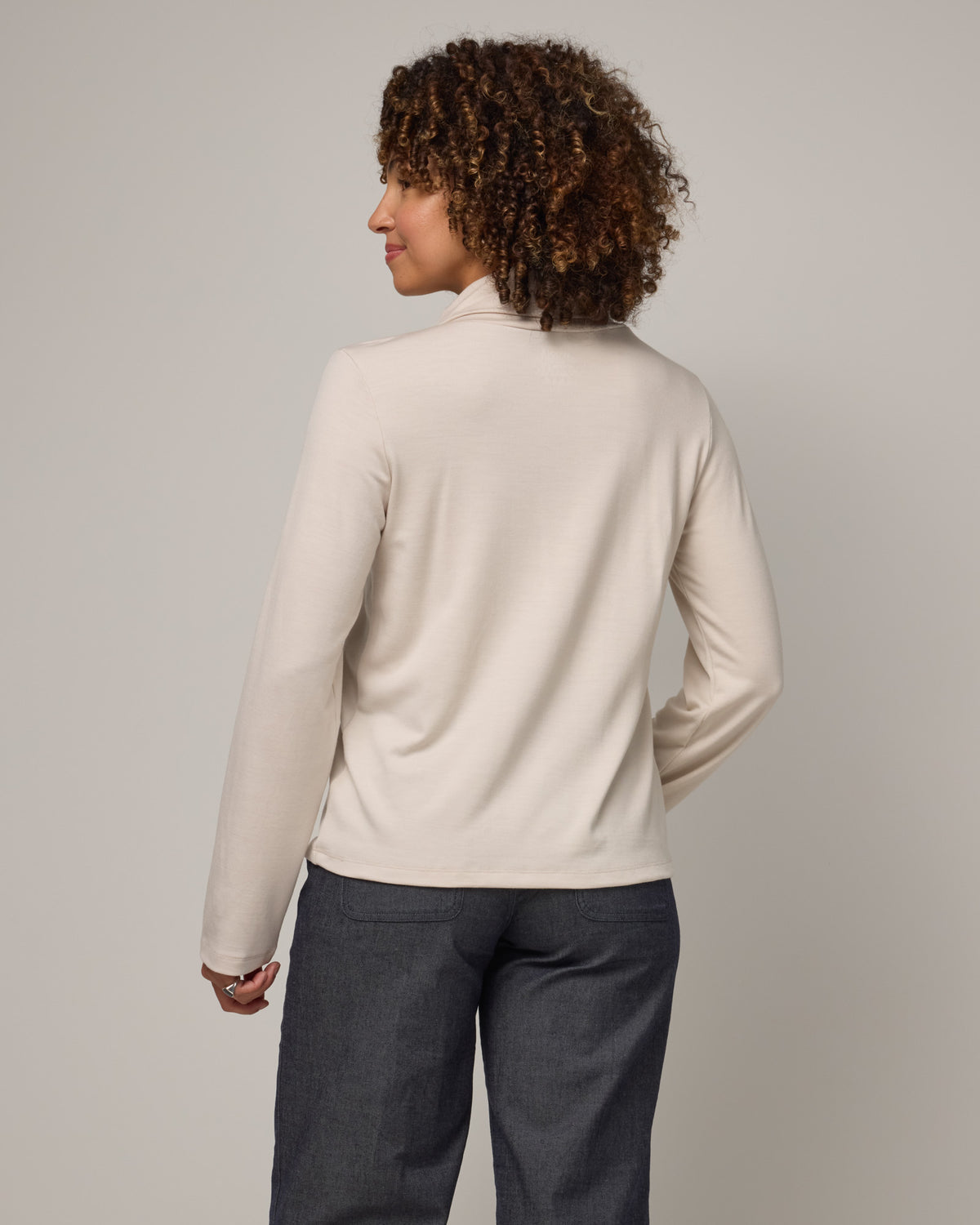 Model wearing Rylie Heavyweight Turtleneck Top in Oatmeal, a light cream color. Rylie Heavyweight Turtleneck Top is a merino wool long sleeve, relaxed fit turtleneck available in sizes XS-3X.