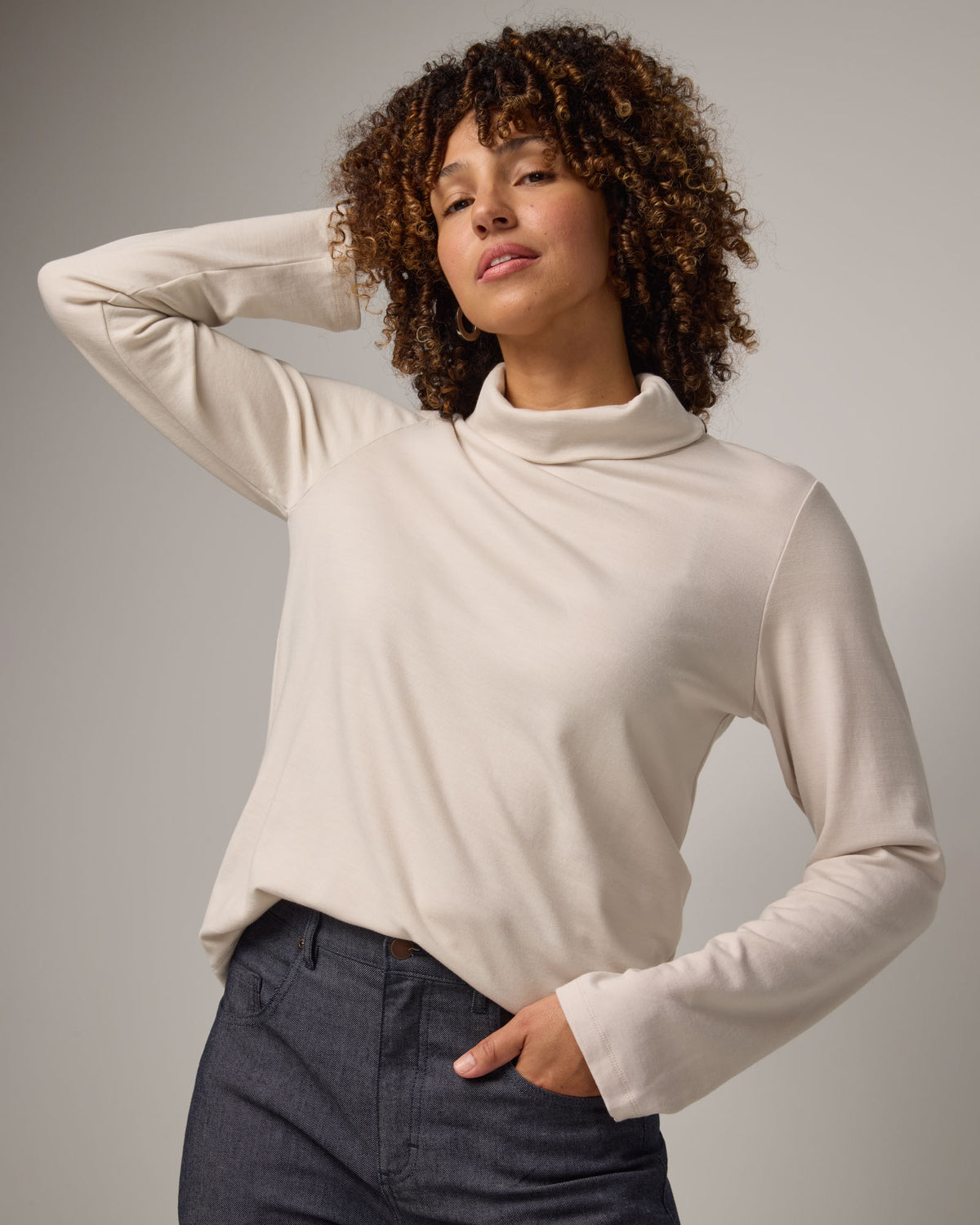 Model wearing Rylie Heavyweight Turtleneck Top in Oatmeal, a light cream color. Rylie Heavyweight Turtleneck Top is a merino wool long sleeve, relaxed fit turtleneck available in sizes XS-3X.